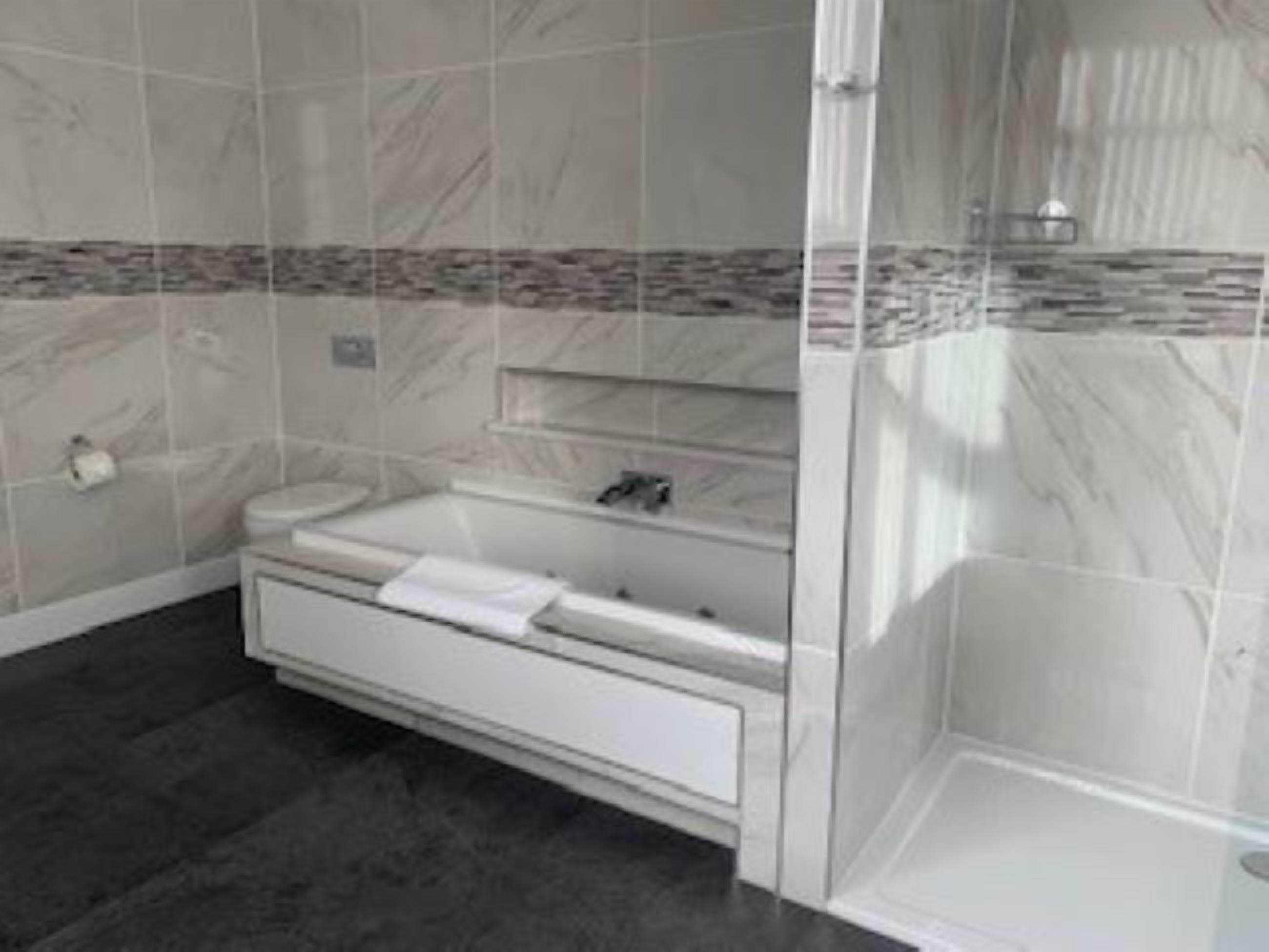 Une salle de bain avec une baignoire blanche, un lavabo et un espace douche.