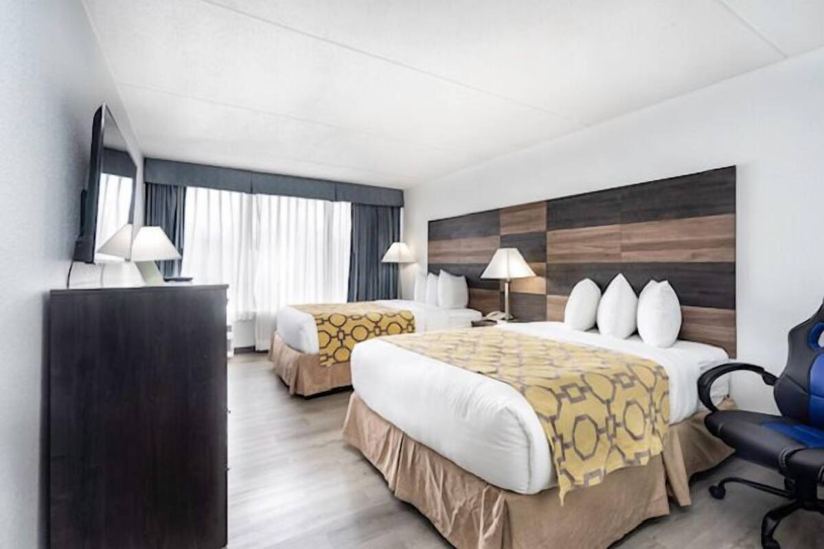 A hotel room with two beds, a large mirror, a desk, and a chair.