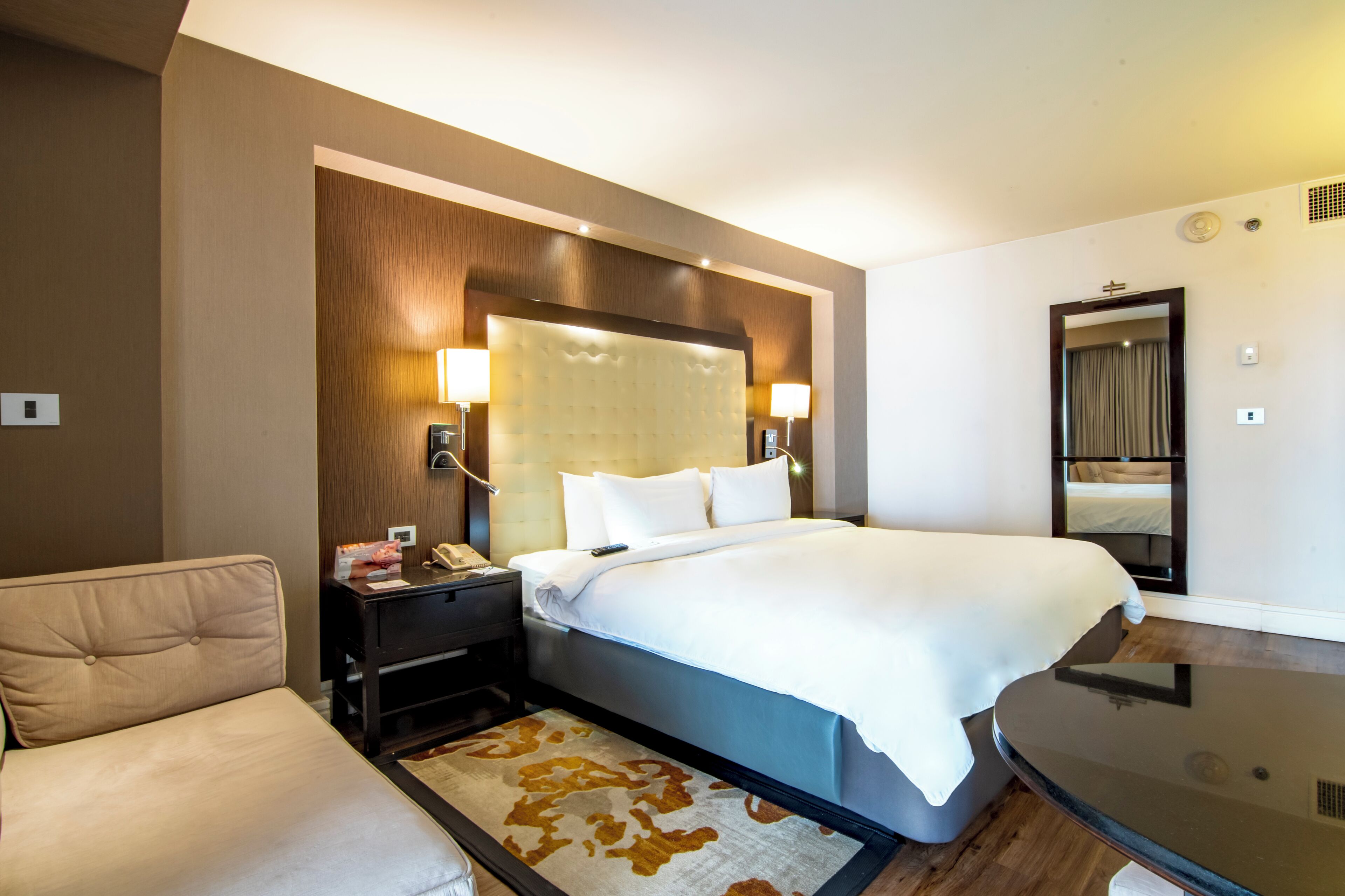 Une chambre d’hôtel avec un grand lit, des lampes de chevet, une table de chevet, un bureau et un miroir.