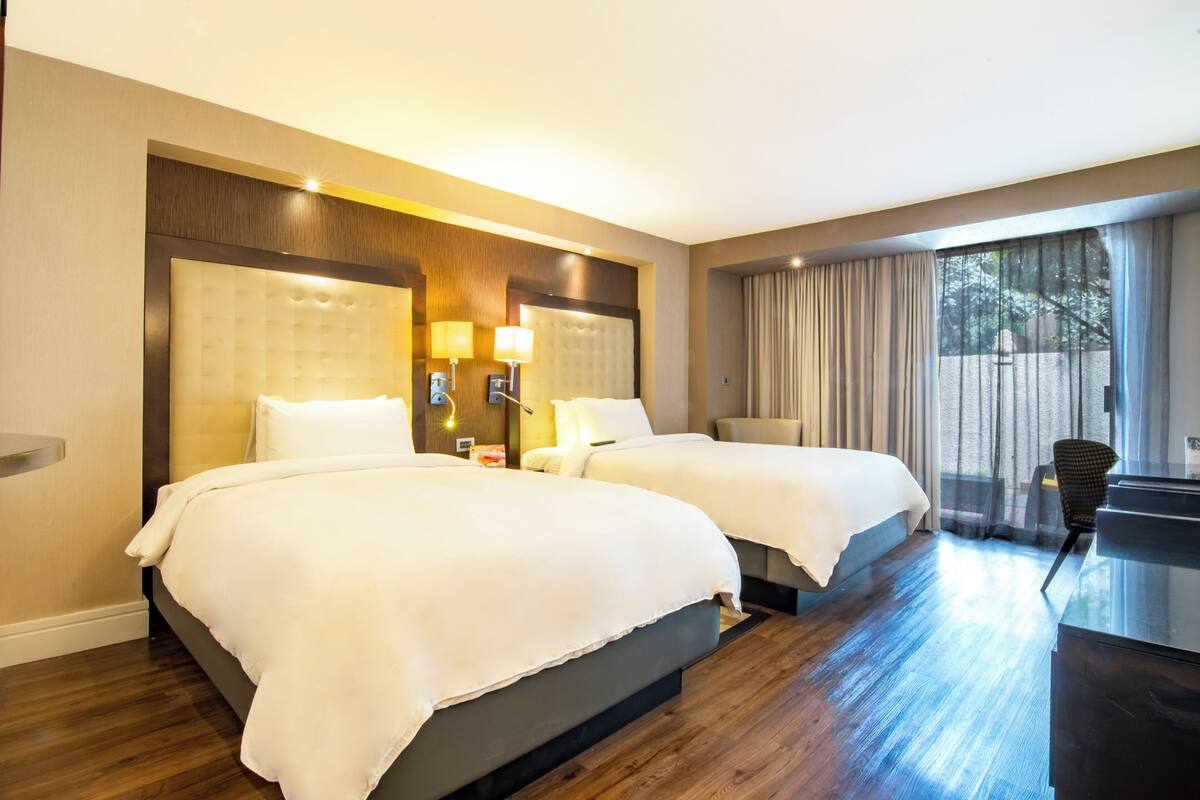 Ein Hotelzimmer mit zwei Betten, einem Schreibtisch und einem Stuhl.