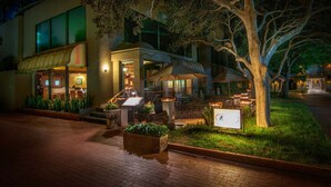 A hotel with outdoor seating, a well-lit entrance, and a large tree in the foreground. - Hotel Lucerna Tijuana (Tijuana)