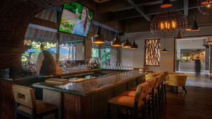 A bar area with a counter, bar stools, and hanging pendant lights. - Hotel Lucerna Tijuana (Tijuana)