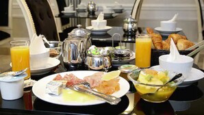 A breakfast setting with various food items, including croissants, fruit, and a selection of cheeses and meats. - Hôtel Eiffel Trocadéro (Paris)