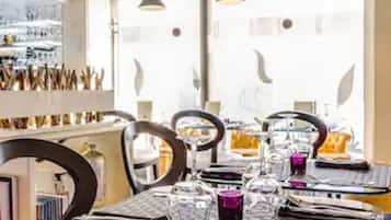 A modern dining area with a glass table, metal chairs, and pendant lighting.