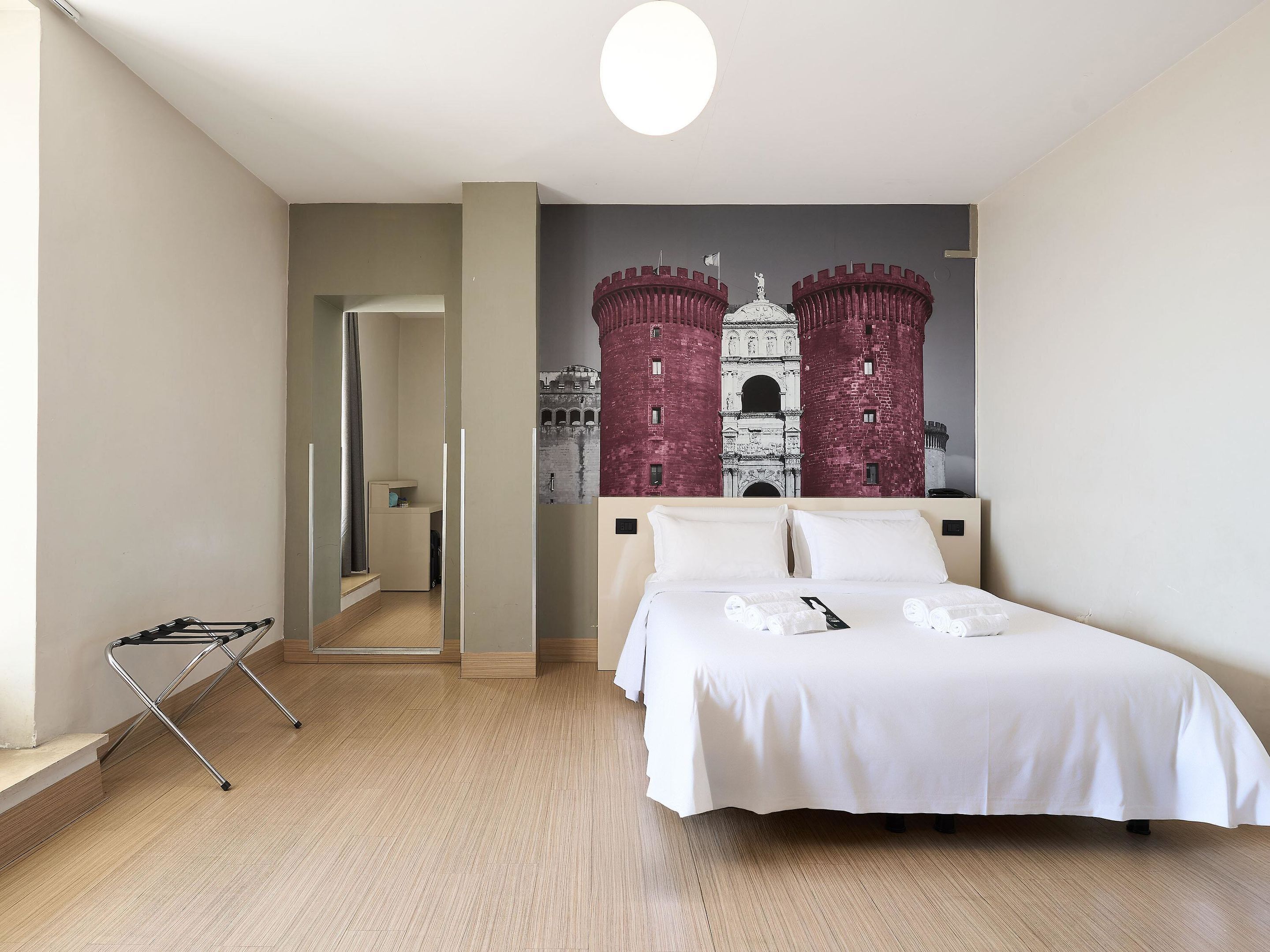A hotel room with a bed, a wheelchair, and a mural of a castle.