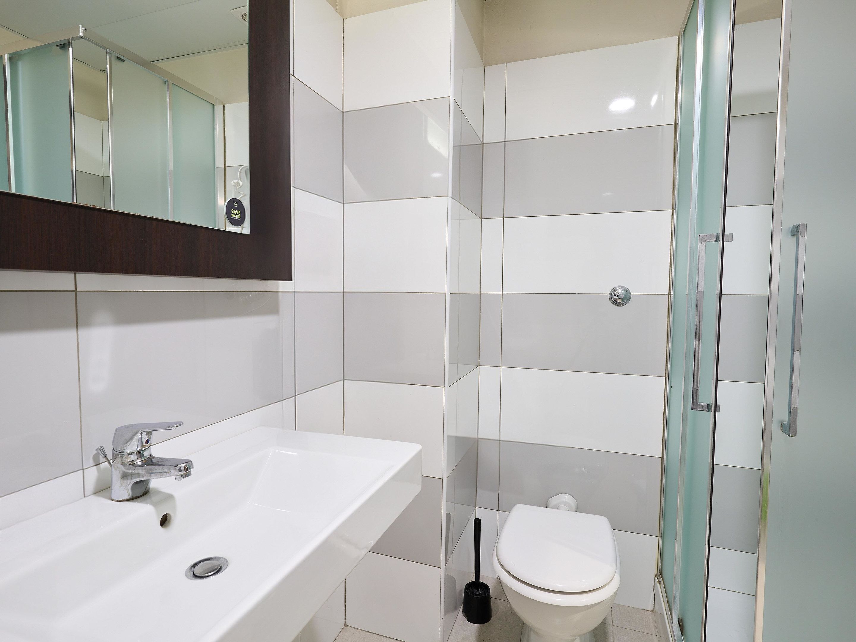 Un bagno moderno con un lavandino bianco, un water e un box doccia in vetro.
