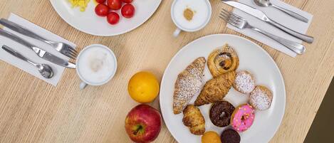 A breakfast spread with various foods and utensils on a wooden table.