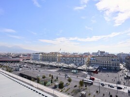 A cityscape with a large open plaza, buildings, and a distant mountain.