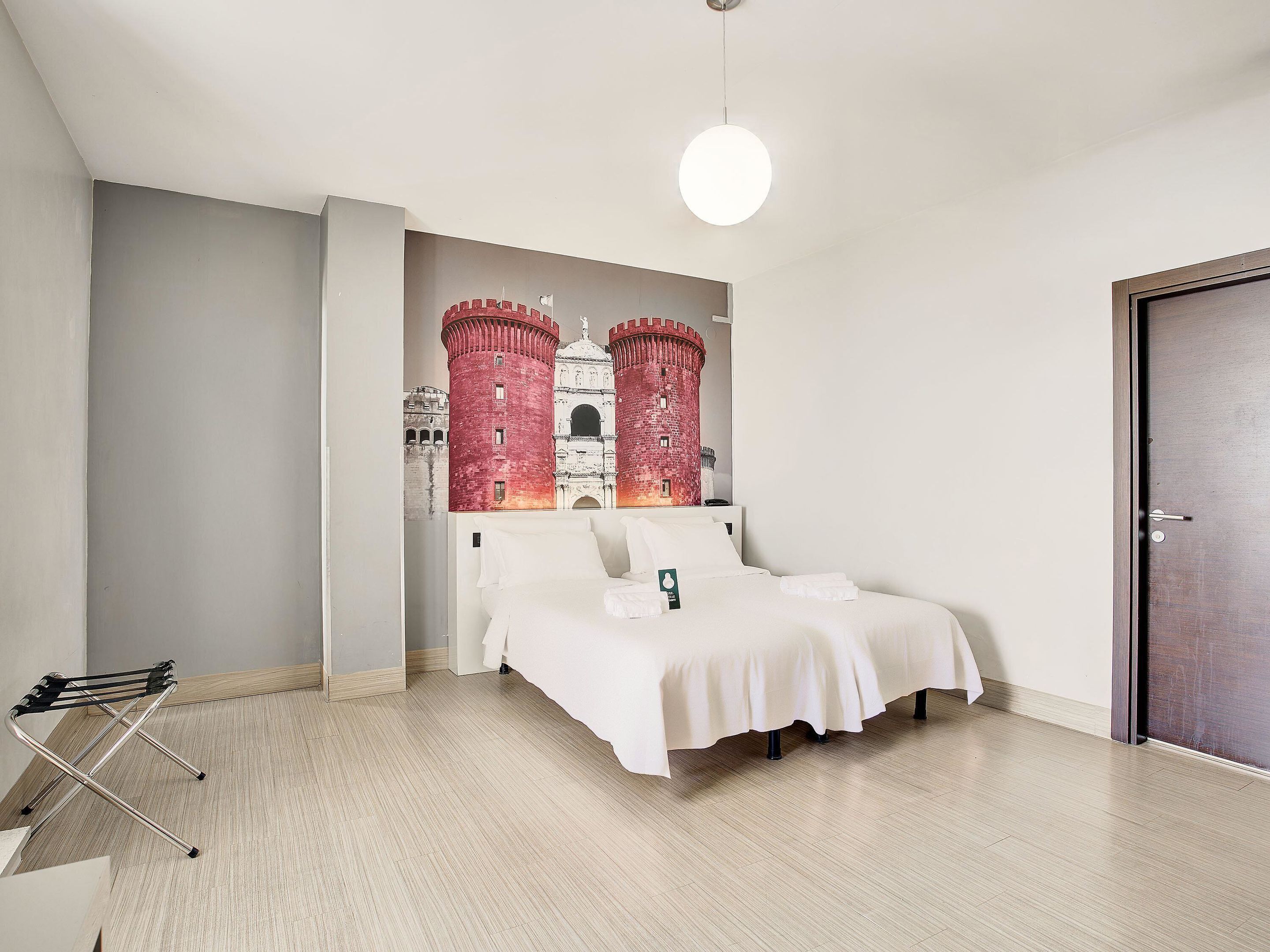 Een slaapkamer met een bed, een hanglamp en een deur.