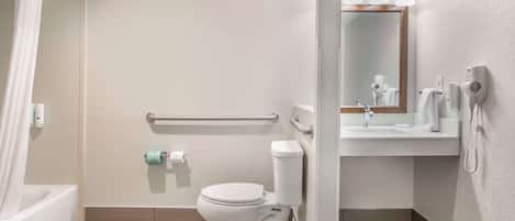 Une salle de bain équipée d’un WC, d’un lavabo, d’un miroir, d’un rideau de douche, d’un sèche-mains et d’un porte-serviettes.