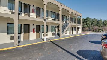A multi-story hotel with balconies, a parking area, and a clear sky.