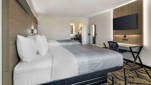 A hotel room with a large bed, a desk, and a flat-screen TV mounted on the wall. - Quality Inn & Suites Athens University Area (Athens)