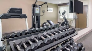 A gym with multiple dumbbells arranged on racks, a treadmill, and a stationary bike. - Quality Inn & Suites Athens University Area (Athens)