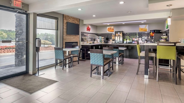 A modern restaurant with a bar area, seating with cushioned chairs, and a visible exit sign. - Quality Inn & Suites Athens University Area (Athens)