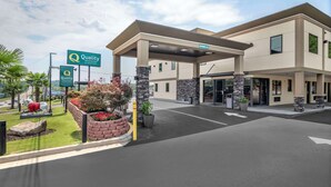 A hotel entrance with a covered parking area, a sign indicating 'Quality by Choice', and a statue of a lion. - Quality Inn & Suites Athens University Area (Athens)