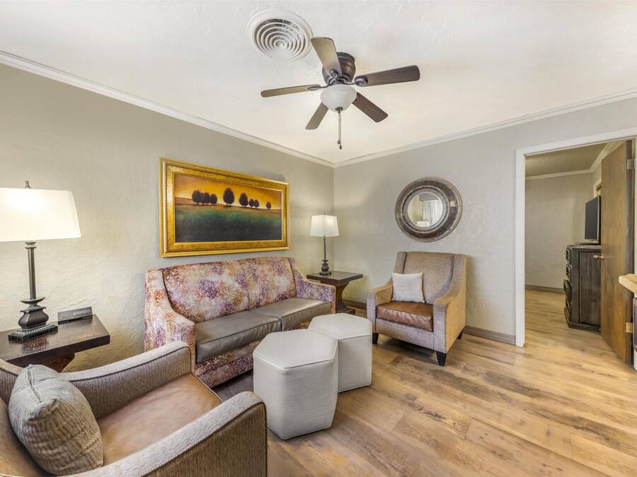 Ein Wohnzimmer mit Deckenventilator, einem floralen Sofa, einem Holztisch und einem Beistelltisch mit Lampe.