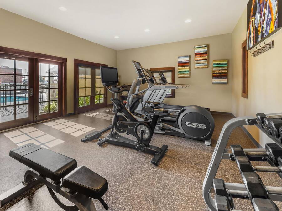 A gym with treadmills, a bench, and dumbbells.