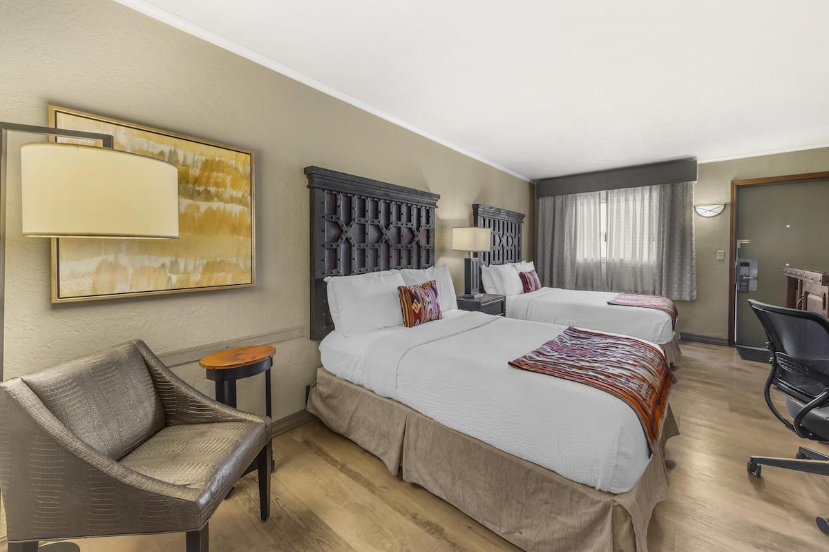 A hotel room with two beds, a sofa, a desk, and a chair.