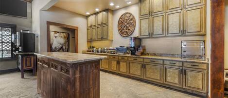 A spacious kitchen with a large island, wooden cabinets, and a stone floor.