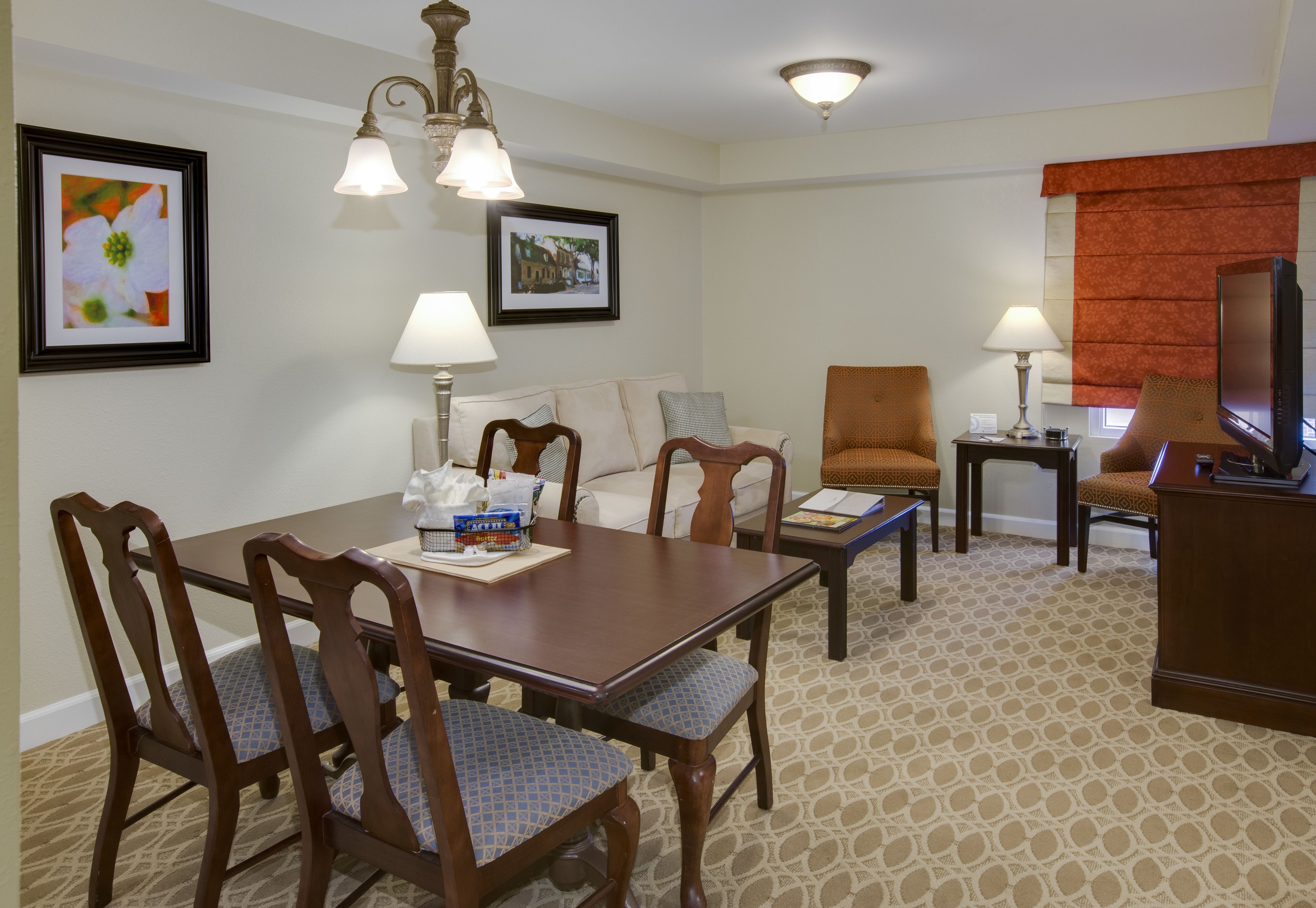 Une chambre d’hôtel équipée d’une table à manger, de chaises, d’un téléviseur et de deux lampes.