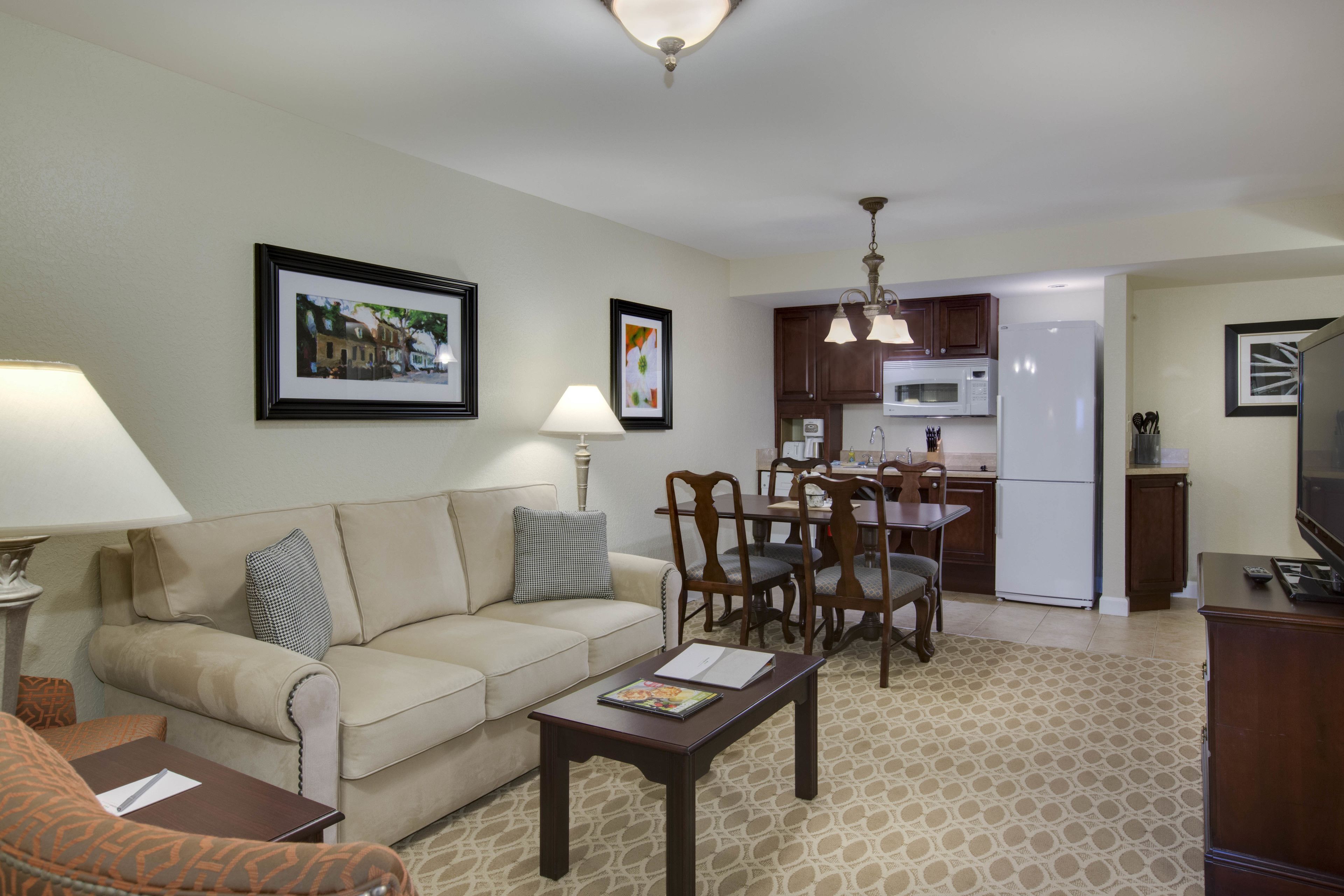 A living room with a sofa, coffee table, and a dining area with chairs and a table.