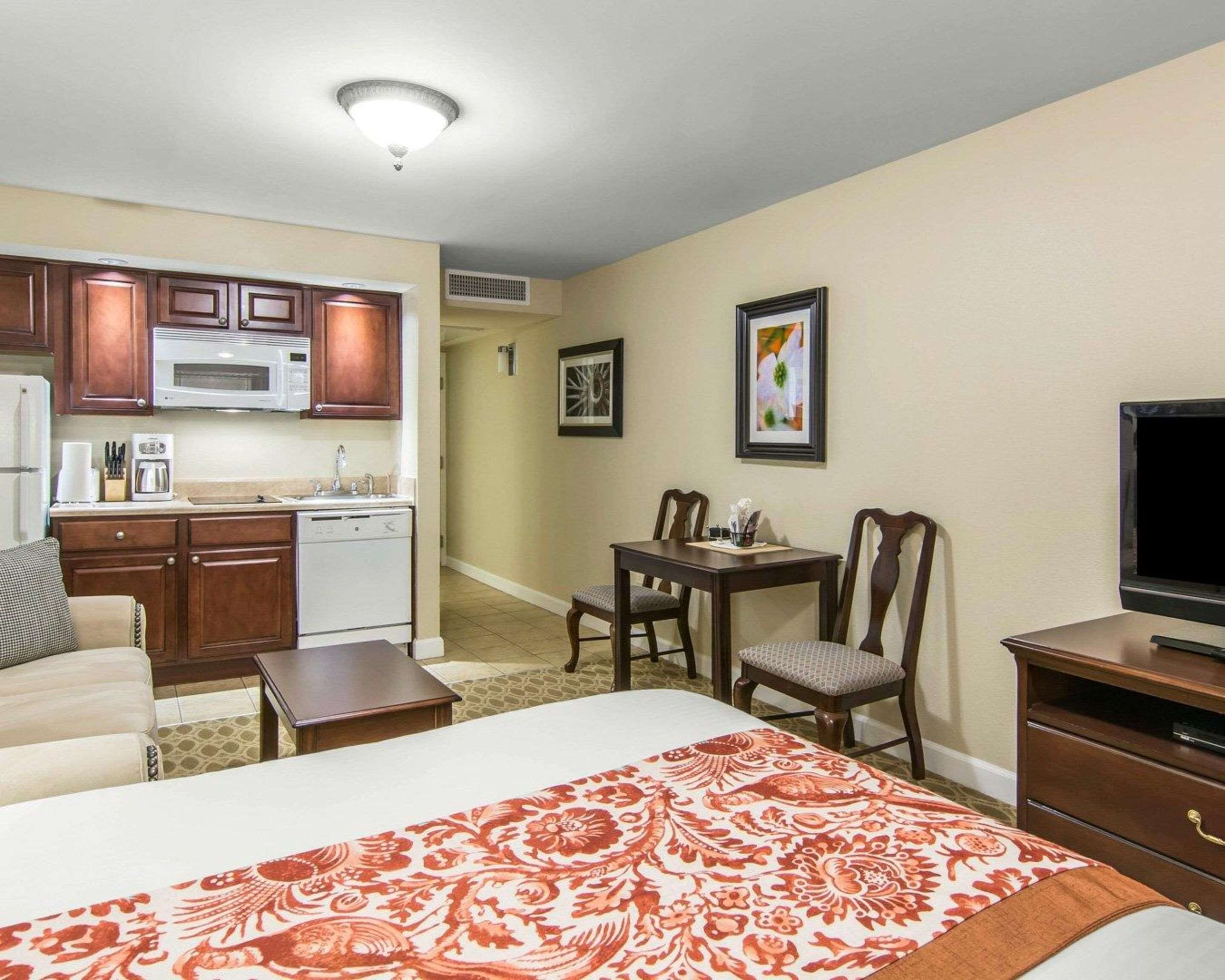 Une chambre d’hôtel équipée d’une kitchenette, d’un coin repas, d’un lit avec une couvre-lit à motifs, d’une télévision et d’une commode.