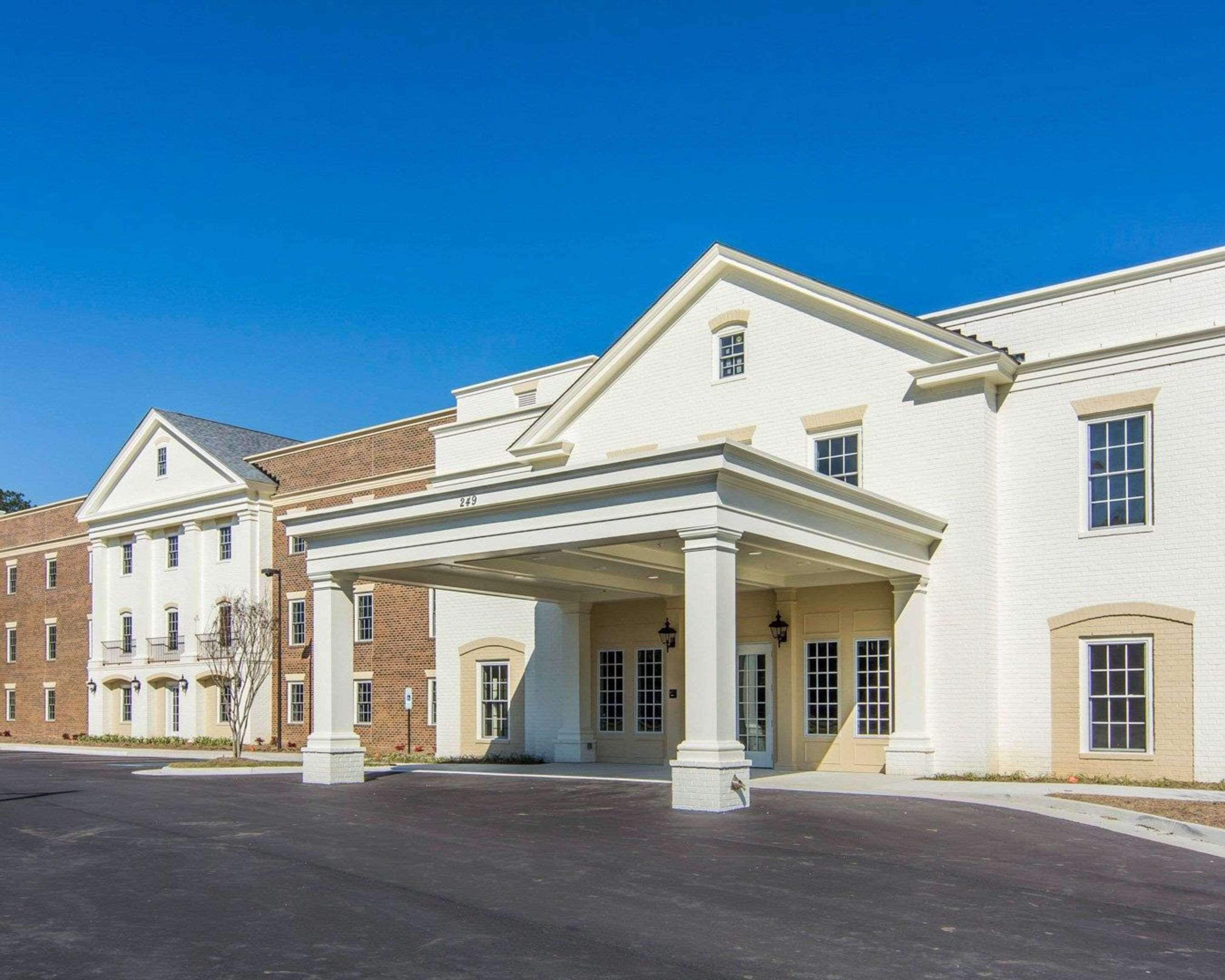 A large, white building with a covered entrance and multiple windows.