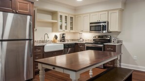 A modern kitchen with stainless steel appliances, wooden cabinets, and a marble countertop. - Bluegreen Vacations Patrick Henry Square, an Ascend Collection Resort (Williamsburg)