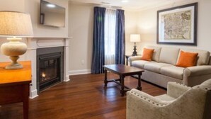 A living room with a fireplace, a sofa, a coffee table, and a lamp. - Bluegreen Vacations Patrick Henry Square, an Ascend Collection Resort (Williamsburg)