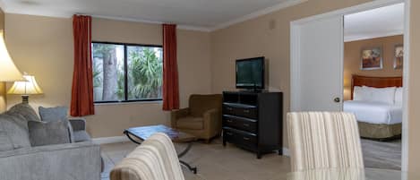 Ein Hotelzimmer mit Sofa, Sessel, Fernseher und Bett.