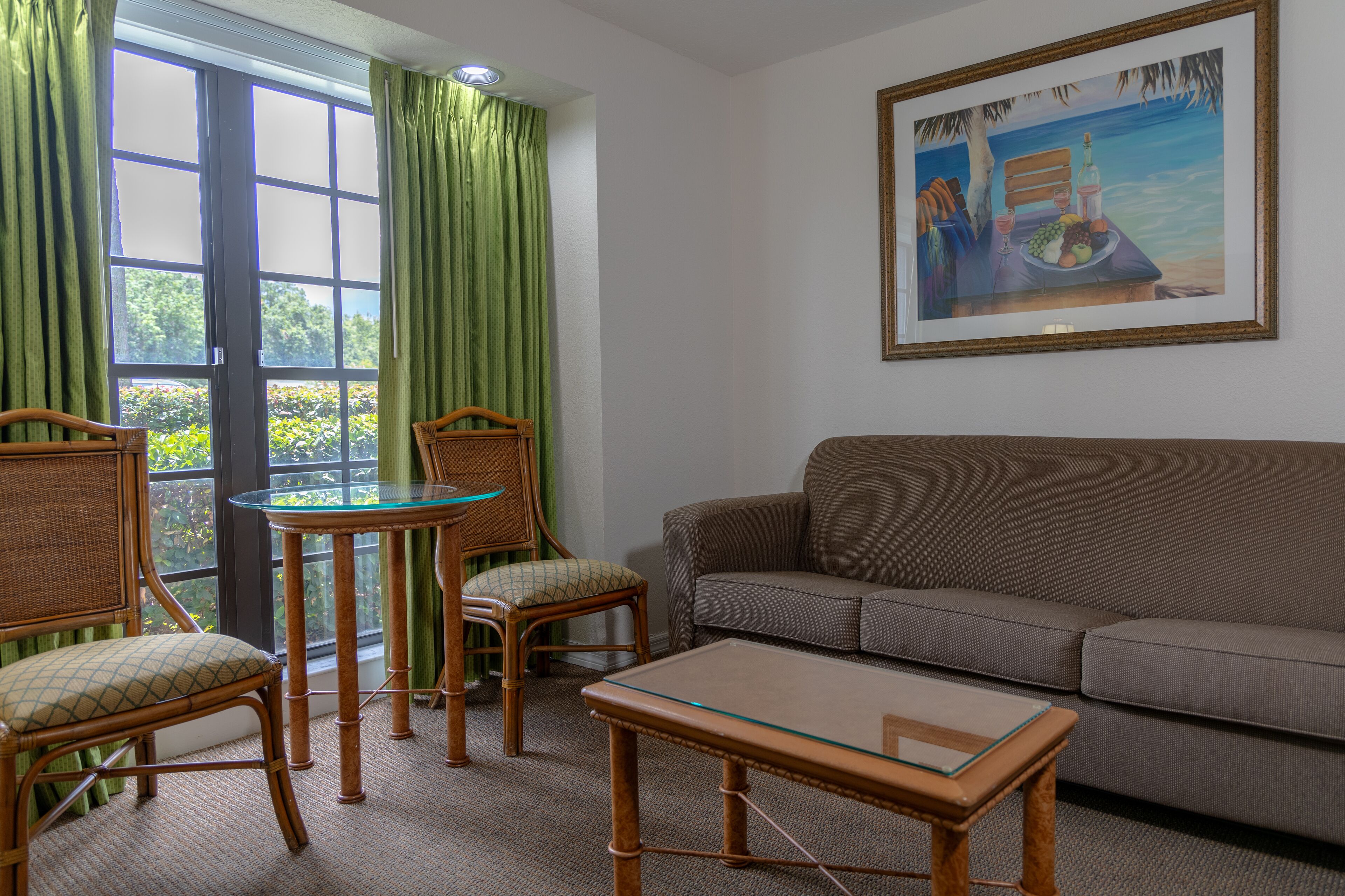 A living room with a sofa, two chairs, a glass-top coffee table, and a painting on the wall.