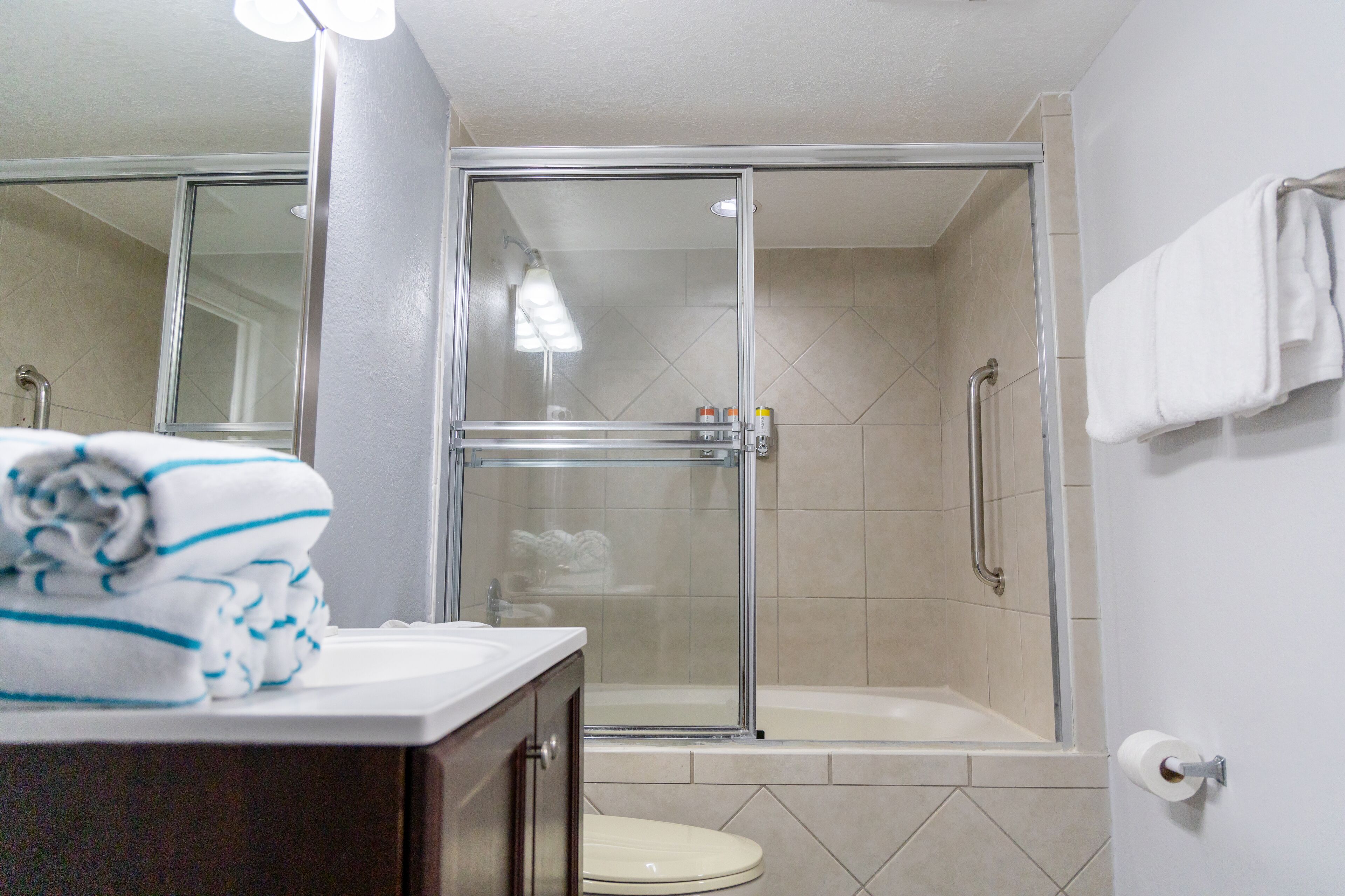 A bathroom with a glass-enclosed shower, a white toilet, and a sink with a towel on the counter.