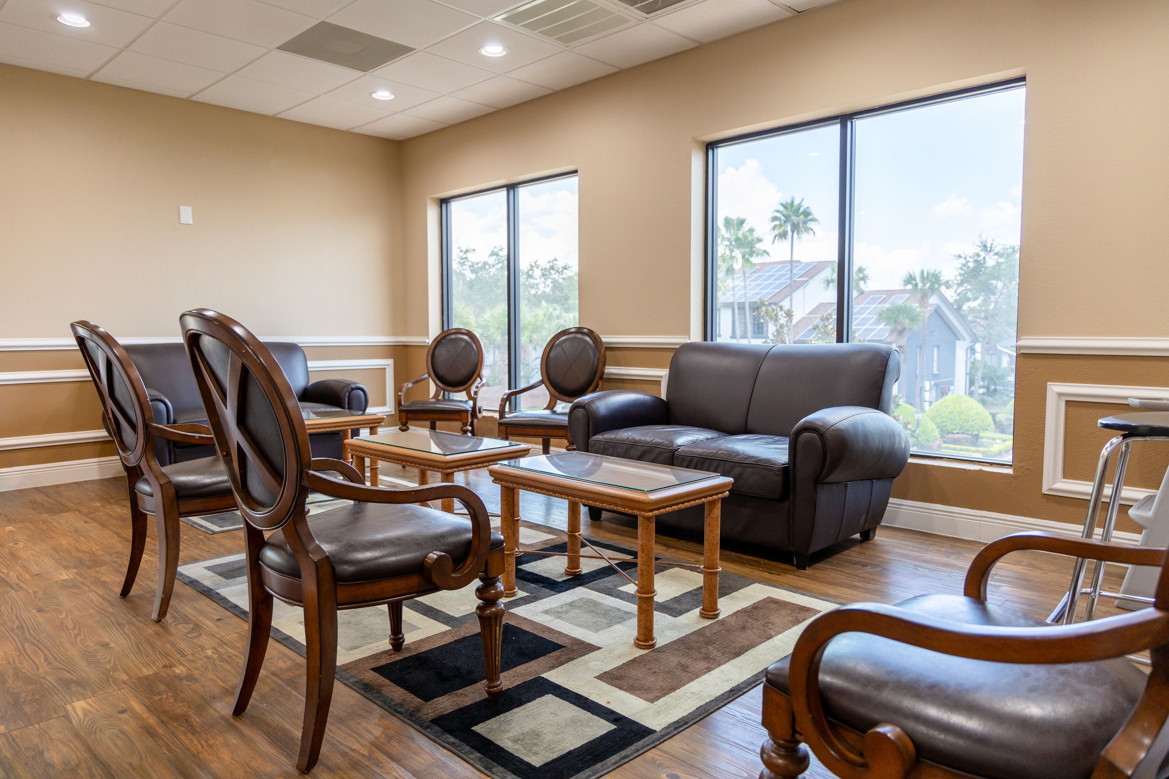 A spacious living room with a leather sofa, wooden chairs, and a glass coffee table.