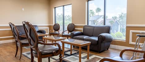 A spacious living room with a leather sofa, wooden chairs, and a glass coffee table.