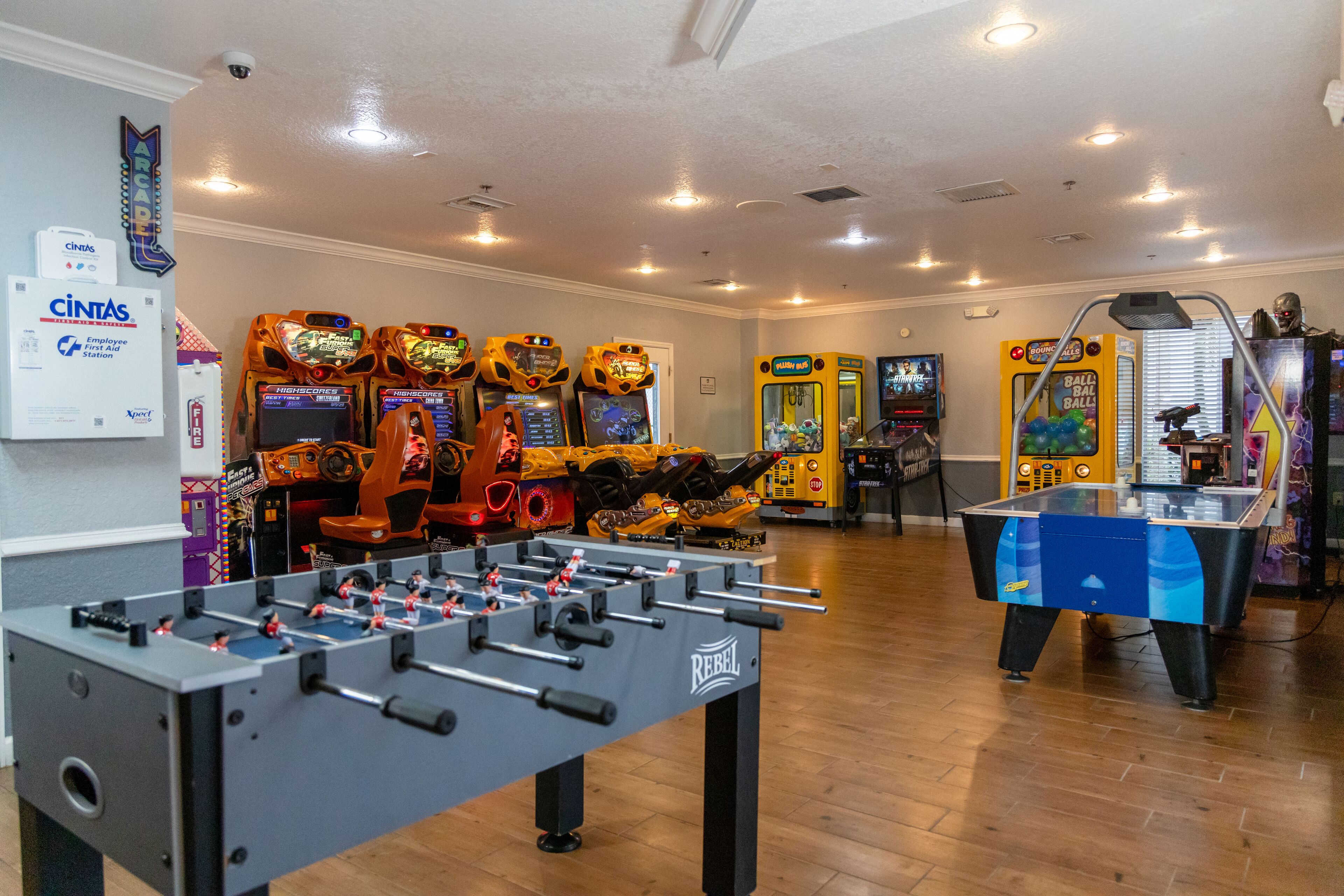 A room with a foosball table, multiple arcade games, and a billiards table.