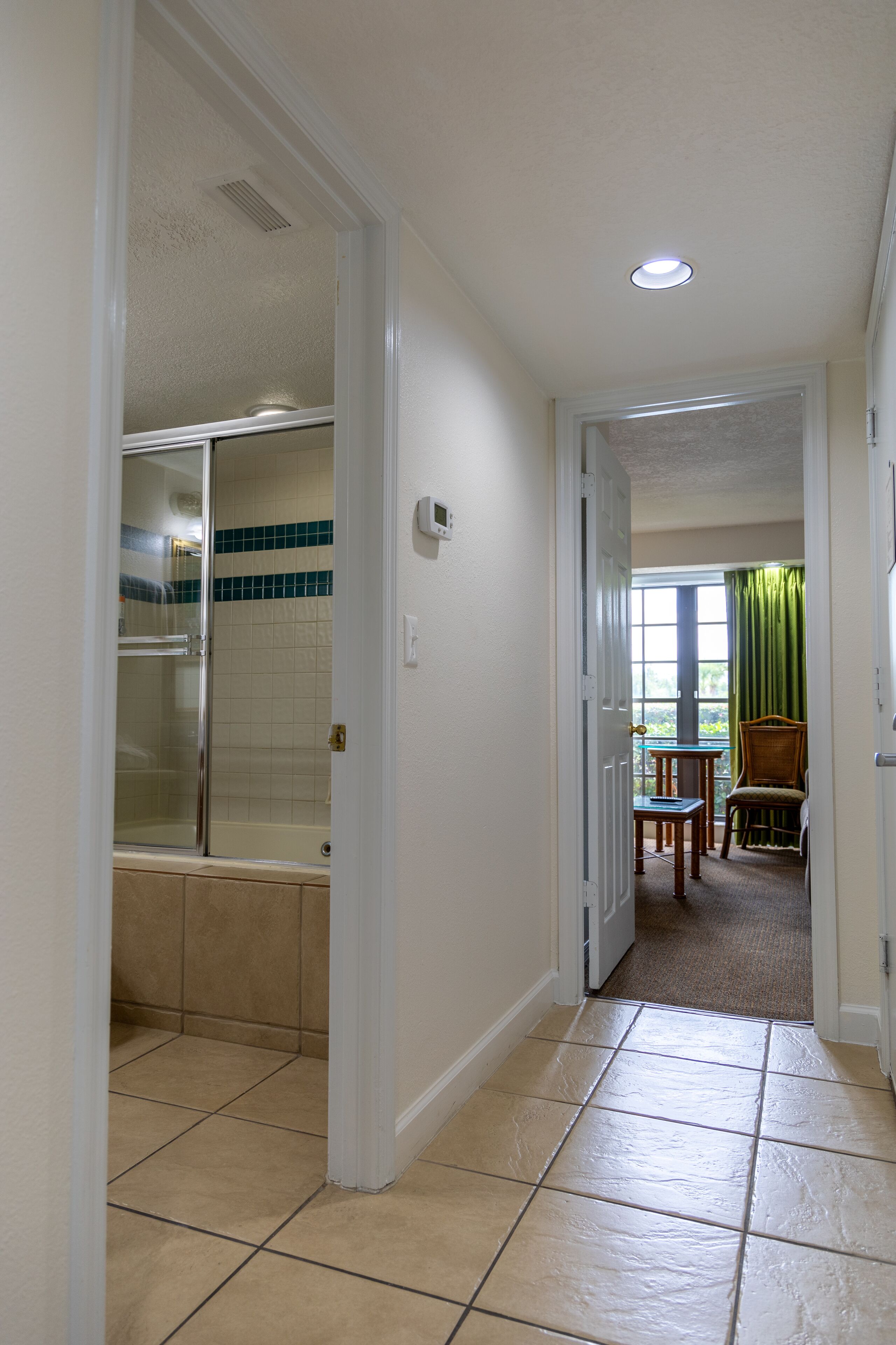 Un couloir avec une douche, un coin repas avec une table et des chaises, et une vue sur l’extérieur par une fenêtre.