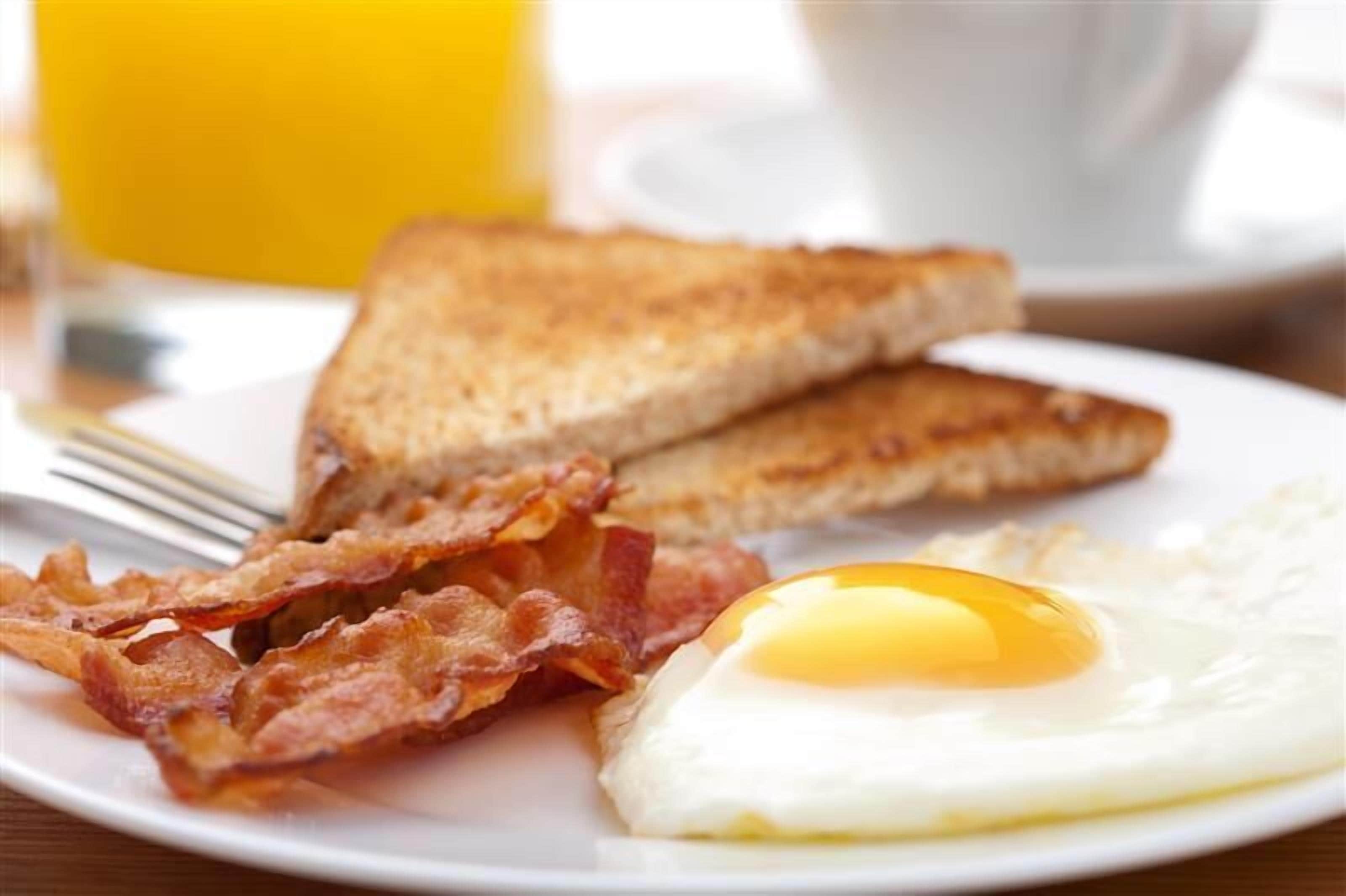 A plate with toast, bacon, and a fried egg.