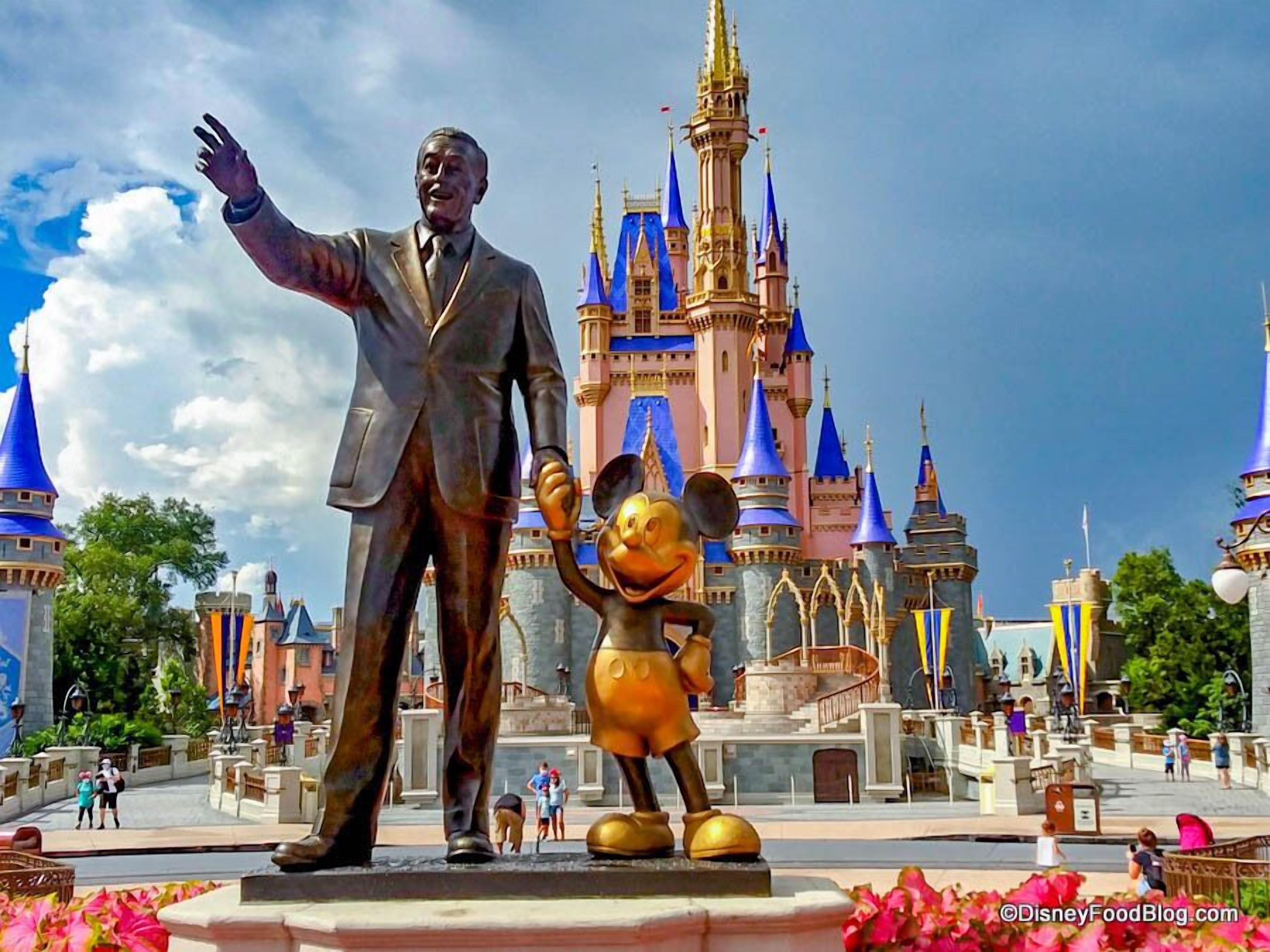A statue of a man and a character in front of a castle-like building.
