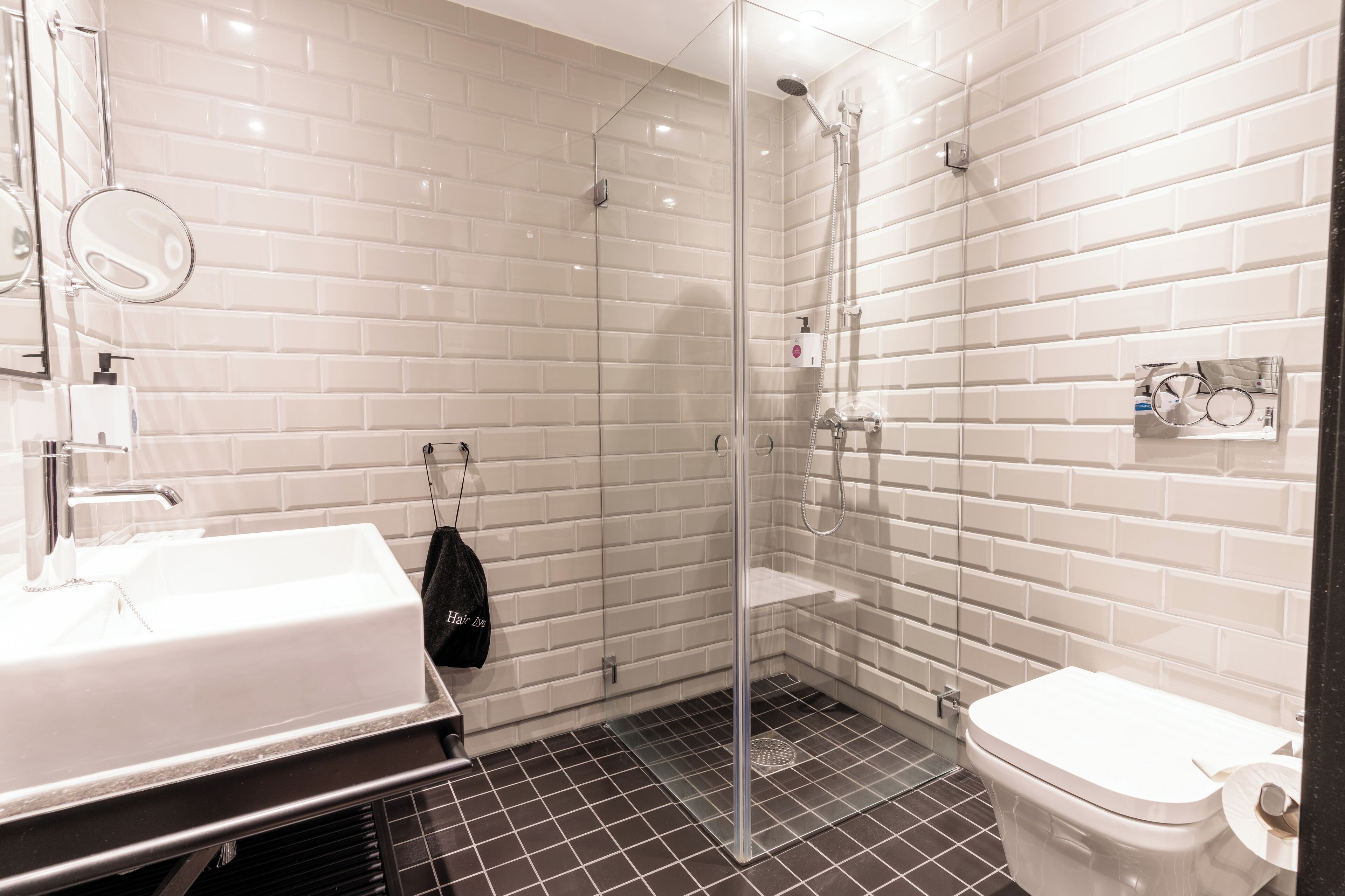 Un baño moderno con ducha envuelta en vidrio, un lavabo blanco y un inodoro.