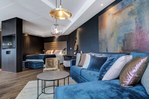 Un salon moderne avec un canapé bleu, une table basse ronde et un grand tableau abstrait accroché au mur.