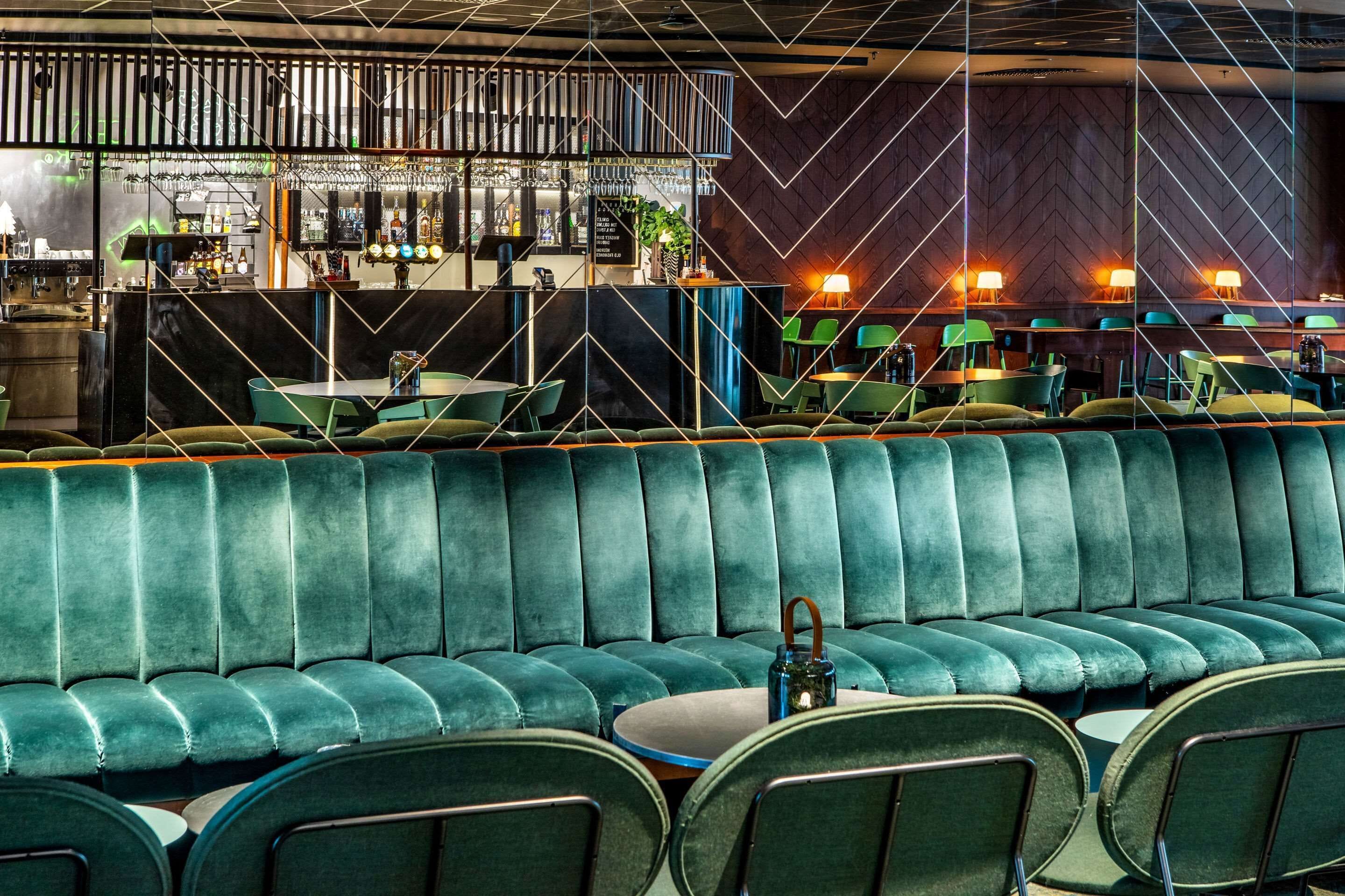 A modern bar area with a bar counter, seating area, and a decorative wall with geometric patterns.