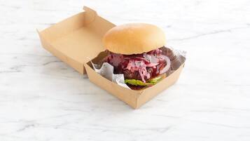 A burger in a cardboard box on a marble surface.