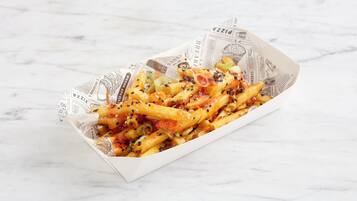 A tray of food with fries and vegetables on a marble surface.
