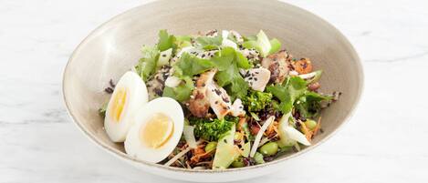 A bowl of salad with various vegetables and a boiled egg.