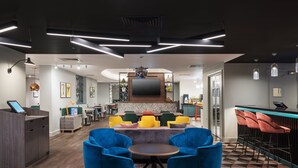 A modern lounge area with a bar, seating, and a large flat-screen TV.