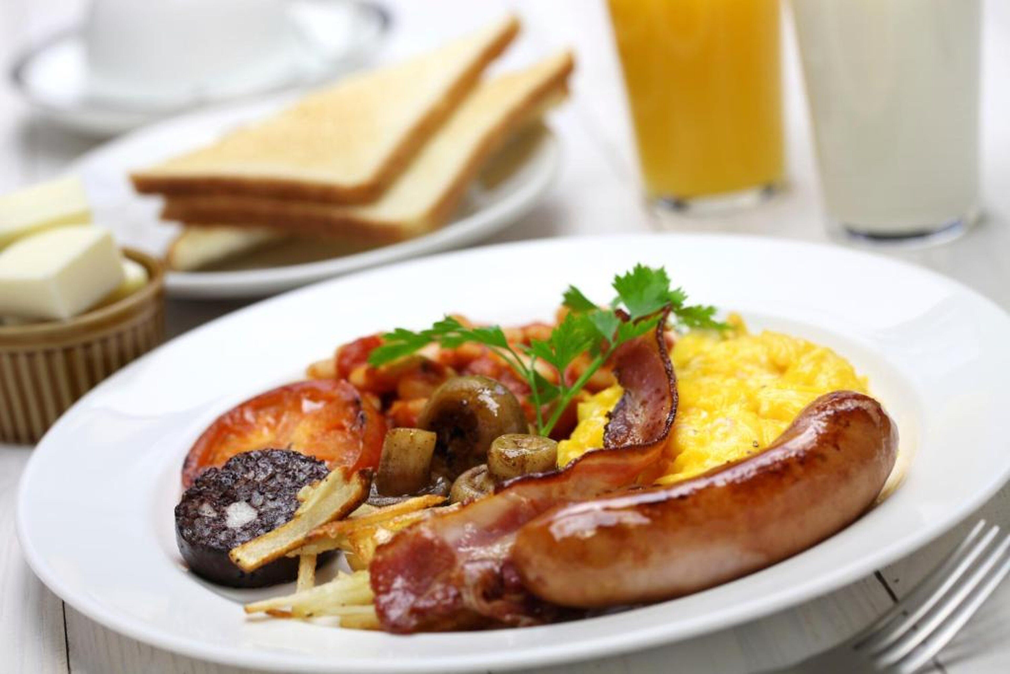 A plate of breakfast food including sausages, eggs, and vegetables.
