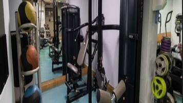 Un gimnasio con equipamiento de ejercicio, una banca y un estante de pesas.