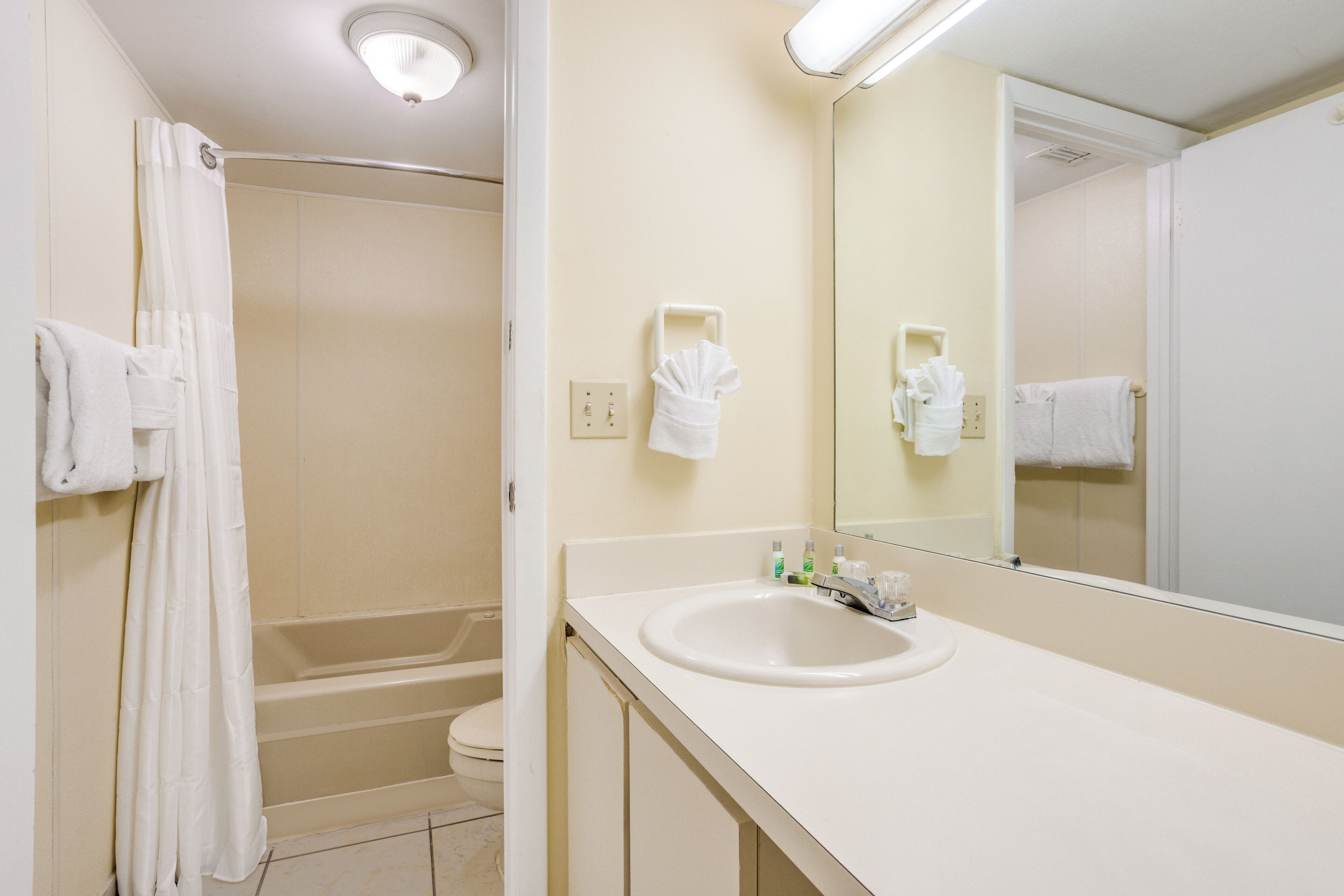 A bathroom with a bathtub, toilet, sink, and a mirror.