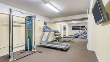 Un gimnasio con cinta de correr, banco de pesas y diversas máquinas de ejercicio.