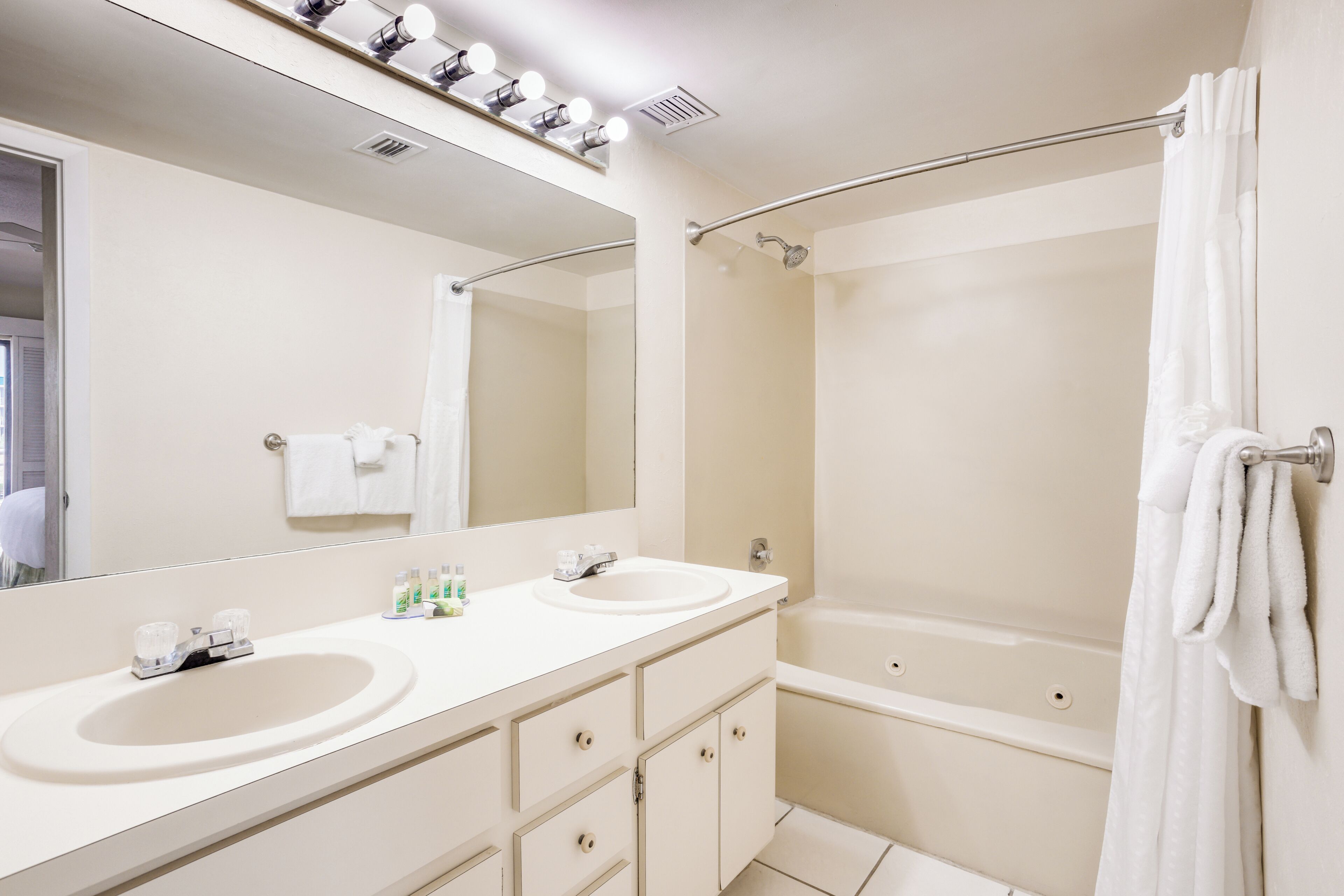 Une salle de bain avec deux lavabos, un grand miroir, une douche et un porte-serviettes.